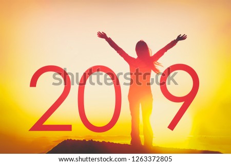 2019 text background for Happy New Year Celebration concept. Woman joyful with open arms in freedom at sunset, silhouette of person winning with resolution goals.