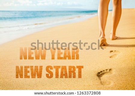 New Year 2019 New Start resolution concept. Beach woman legs feet walking barefoot on sand leaving footprints in sunset. Vacation travel freedom people.