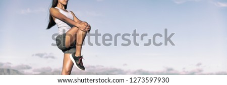 Runner stretching legs hamstring muscles outdoor holding one leg standing outdoor in sky background banner panorama. Running athlete woman doing fitness stretch.