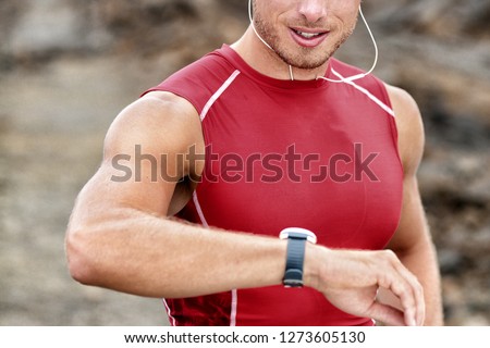 Smartwatch man athlete runner checking his wearable device tech smart watch during outdoor training - intense cardio workout exercise.
