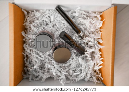Makeup products online shopping delivery box at home - Gift box containing mascara, eyeliner, eyeshadow cream for blush or concealer.