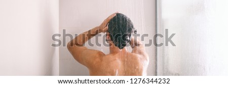 Shower man washing hair rinsing shampoo in bathroom banner panorama. Showering person at home lifestyle. Young guy taking a shower.