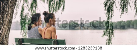 Mom and daughter happy relaxing together at Beijing summer palace lake park enjoying quiet summer day traveling in China. Two women relaxing peaceful on park bench. Asian women, banner panorama.