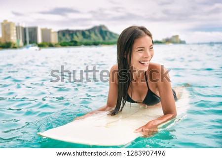 Surf class in Waikiki Hawaii - Surfing Asian surfer girl on surfbaord lesson in Hawaii paddling in ocean waves. Sexy sports athlete training in water. Watersport active lifestyle.