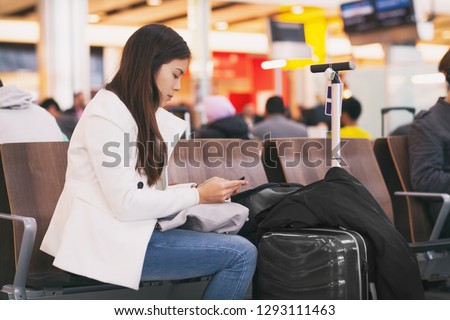 Airport girl passenger on mobile phone waiting for delayed flight sitting at terminal gate with luggages. Bored and tired person.