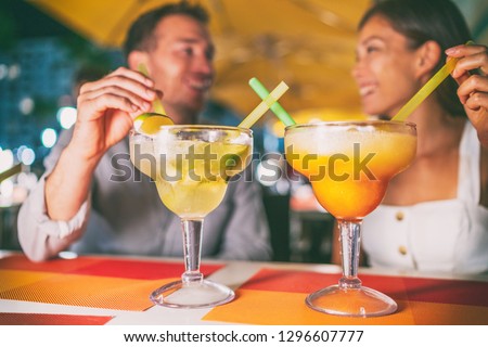 Night out drinking giant margaritas cocktails party couple going out at Miami Ocean drive restaurant having fun. Funny drinks at outdoor terrace young people travel lifestyle.