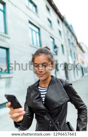Phone young trendy chinese woman walking on city street using mobile smart phone texting message on messaging shopping app online on cellphone outside. Urban young people lifestyle . Technology.