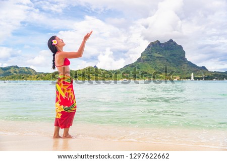 Polynesian hula dancer woman dancing on Bora Bora beach Hawaii traditional dance for luau party. Happy Asian tourist learning to dance in front of Mt Otemanu, Tahiti, French Polynesia.