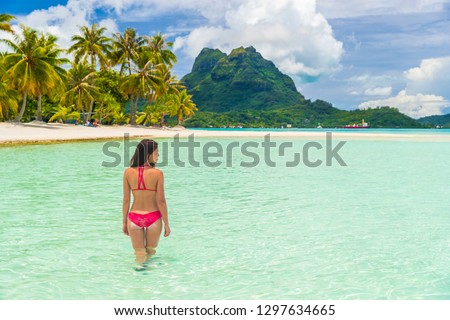 Bora bora luxury vacation travel paradise bikini woman swimming at island in Tahiti, French Polynesia. Popular honeymoon destination holiday in South Pacific, Oceania.