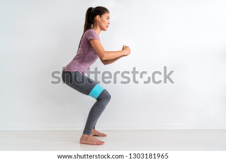 Resistance band fitness woman doing squat exercise with fabric booty band stretching strap. Crab walk squatting workout girl training at home.