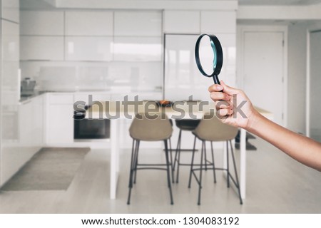 Home inspection - magnifying glass inspector looking at kitchen house background.