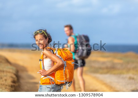 Young happy couple hiking together in nature outdoor. Travel adventure young tourists walking with backpacks in mountain by the ocean.