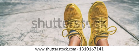 Sport running shoes woman taking feet selfie at gym -banner panorama. Sportswear yellow color fashion trainers with matching socks.