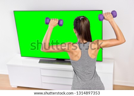 Home workout tv program fitness show online girl watching video training arms with dumbbells.