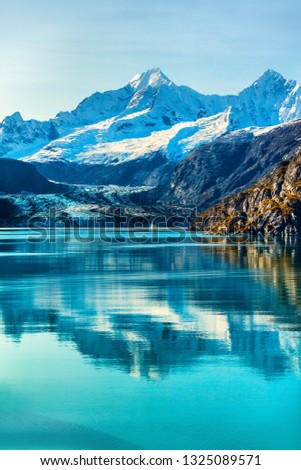 Glacier Bay cruise ship cruising to Johns Hopkins Glacier in Alaska, USA. Summer travel destination for vacation. Mirror water reflection in tranquil arctic sea, famous attraction.