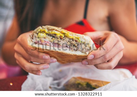 Cuban sandwich closeup woman holding local food at typical cafe outside. Pressed cuban bread with roasted pork, salami sausage, swiss cheese, mustard, typical cuba dish.