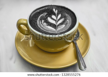 Charcoal latte coffee cup latest food trend. Activated charcoal powder mixed in cappuccino steamed milk froth for healthy detox hangover cure.