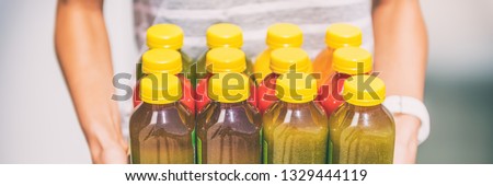 Green smoothie juice bottles box of cold pressed vegetable juices. Woman holding delivery box. Health trend for cleansing of organic raw juices. Juicing for diet cleanse detox. Banner panorama.