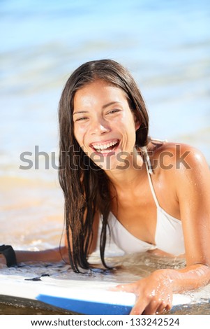 Water sport fun - beach woman bodyboarding surfing on bodyboard or boogieboard. Girl laughing having fun during summer holidays vacation travel. Lifestyle image mixed race Asian Caucasian female model