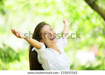 Carefree Elated Cheering Woman In Spring Or Summer Forest Park Full Of Hope And Vitality. Multiracial Girl Raising Her Arms Up Smiling Happy. Mixed Race Asian Caucasian Female Model.