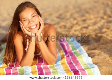 Beautiful Woman Sunbathing On The Beach Lying On A Towel Facing The