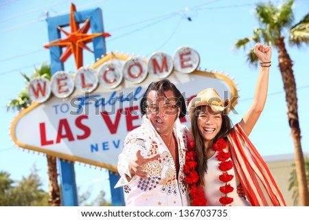 Las Vegas Elvis impersonator having fun cheering by Welcome to Fabulous Las Vegas sign. Funny happy joyful image with Elvis and smiling happy beautiful girl wearing cowboy hat on the Strip
