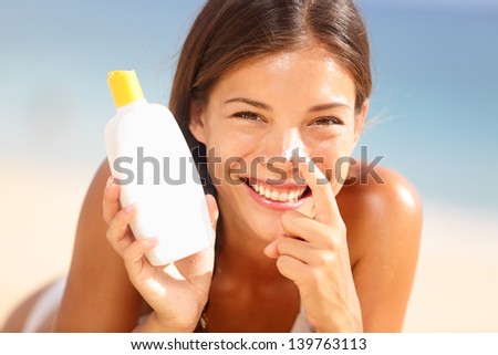 Suntan Lotion Woman Applying Sunscreen Solar Cream. Beautiful Happy Cute Woman Asian Applying Suntan Cream From A Plastic Container To Her Nose With Ocean In Background.