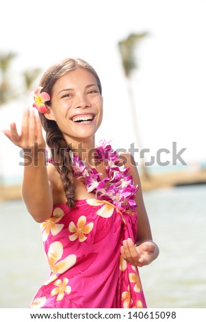 Hula dancer woman dancing hula dance on Hawaii wearing Hawaiian orchid flower lei smiling happy on beach. Travel vacation summer holidays image of beautiful mixed race girl in colorful pink sarong.