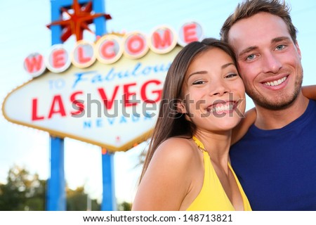 Las Vegas Tourist Couple At Las Vegas Sign. Happy Tourist Couple Taking Self-Portrait In Front Of Welcome To Fabulous Las Vegas Sign. Beautiful Young Multi-Ethnic People, Asian Woman, Caucasian Man.