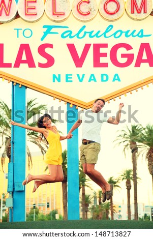 Las Vegas Sign. Happy people jumping having fun in front of Welcome to Fabulous Las Vegas sign. Beautiful young couple on the Strip cheerful and excited during travel holidays vacation, Nevada, USA.