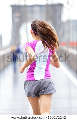 City runner - woman running on Brooklyn Bridge. Rear view backside close up of female athlete training outside in rain in New York City, United States.