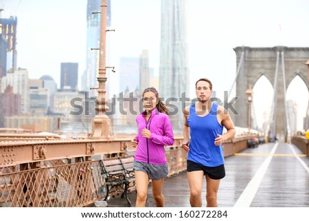 Running Couple. Runners Jogging Outside In Rain. Asian Woman And Caucasian Man Runner And Fitness Sport Models Training Outdoor On Brooklyn Bridge, New York City, Usa.