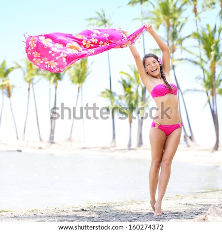 Beach woman waving scarf. Happy and free asian girl enjoying vacation holiday on beach travel resort with palm trees. Beautiful mixed race Asian Caucasian female in pink bikini on Big Island, Hawaii.