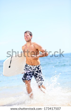 Summer beach fun surfer man running with bodyboard. Fit fitness model doing water sport bodyboarding surfing. Photo from Kaanapali beach, Maui, Hawaii.
