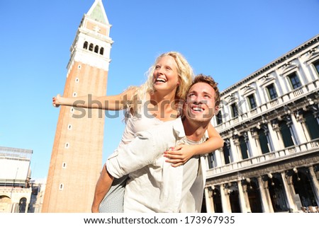 Romantic Couple In Love Having Fun Embracing And Laughing Doing Piggyback Ride In Venice, Italy On Piazza, San Marco. Happy Young Couple On Travel Vacation On St Mark'S Square. Happy Woman And Man.