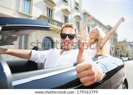 Car driver happy giving thumbs up - driving couple excited on road trip travel vacation. Male driver wearing sunglasses. Lifestyle with beautiful cheerful lovers, man and woman.