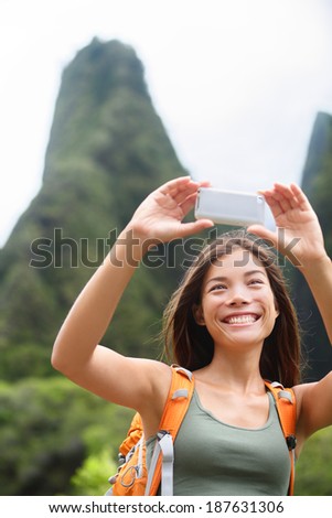 Woman hiker taking selfie photo using smartphone while hiking on Hawaii enjoying outdoor activity. Woman hiker taking photo with smart phone camera. Iao Valley State Park, Wailuku, Maui, USA.