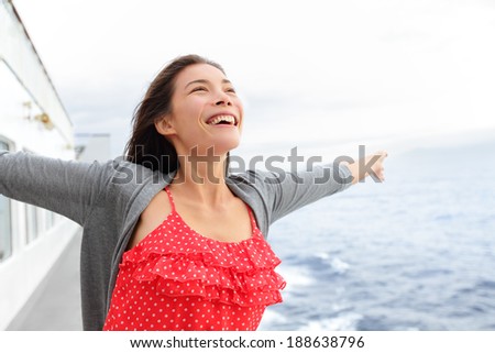 Cruise ship woman on boat in happy free pose smiling enjoying freedom. Young woman traveling on vacation travel sailing on open sea ocean. Young mixed race Asian Caucasian woman.