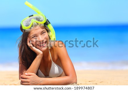 Woman on beach vacation holidays with snorkel lying in sand with snorkeling mask and fins smiling happy enjoying the sun on sunny summer day. Multi ethnic Asian Chinese / Caucasian woman model.