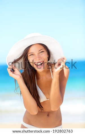 Beach woman happy on travel laughing cute enjoying sun tanning on travel smiling under blue sky. Cheerful beautiful bikini girl having fun on beach. Fresh mixed race Asian Caucasian model on holidays.