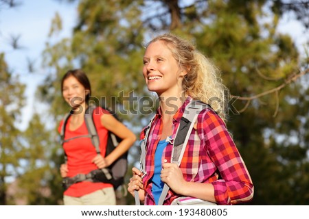 Active women - hiking girls walking in forest living healthy lifestyle doing outdoor activities. Female hikers trekking outside in woods wearing backpacks. Portrait of beautiful young blond hiker.