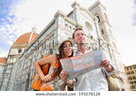 Tourist travel couple by Florence cathedral, Italy looking at map in front of Il Duomo di Firenze also called Basilica di Santa Maria del Fiore. Main tourist attraction and landmark in Florence, Italy