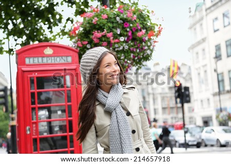 People in London- woman by red phone booth. Portrait of beautiful smiling happy young female casual professional business woman walking outside in City of Westminster, London, England, Great Britain.