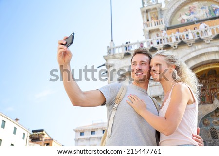 Couple on travel taking selfie photo Venice, Italy on Piazza San Marco in front of Saint Mark\'s Basilica. Happy young couple on vacation in Europe. Happy woman and man in love traveling together.