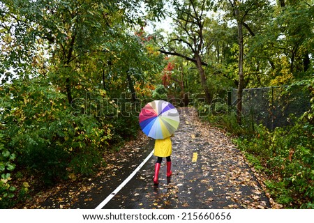 Autumn / fall concept - woman walking in forest with umbrella in rain. Girl enjoying rainy fall day.