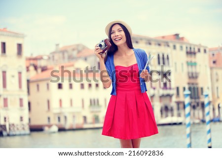 Travel tourist woman with camera and map in Venice, Italy. Vintage retro style Asian girl on vacation smiling happy by Grand Canal. Mixed race Asian Caucasian girl having fun traveling outdoors.