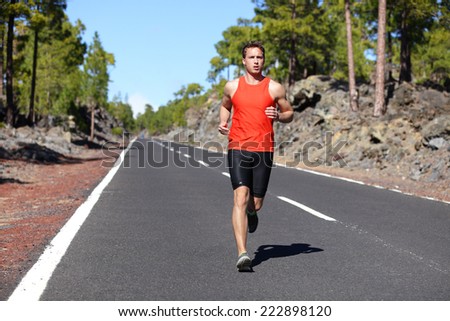 Running man - male runner jogging outdoors on road training for marathon run as part of healthy lifestyle. Close up of fit fitness model during outdoor workout in summer. Caucasian guy.