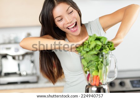 Vegetable smoothie woman making green smoothies with blender home in kitchen. Healthy raw eating lifestyle concept portrait of beautiful young woman preparing drink with spinach, carrots, celery etc.