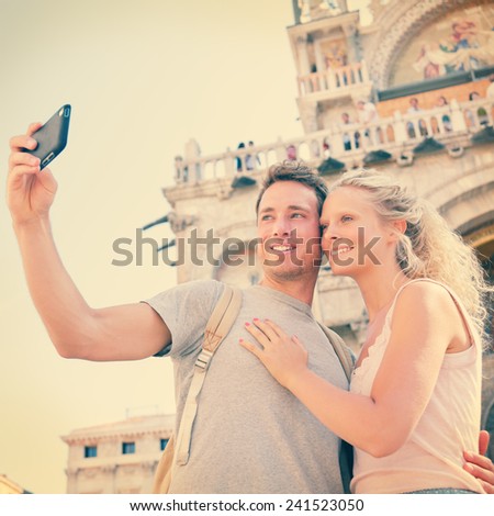 Selfie travel couple in love taking photo with smartphone, Venice, Italy, Piazza San Marco by Saint Mark's Basilica. Happy young couple on vacation in Europe. Woman and man in love traveling together