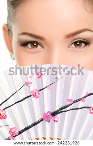 Asian eyes woman. Eye makeup asian look with paper fan. Beauty portrait of mixed race Asian / Caucasian female model on white background. Close up on eyes.